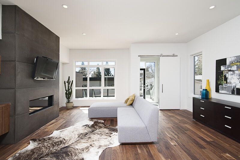 Interior design photography in Arlington, Virginia capturing a cozy sunroom with natural light, rattan furniture including a hanging chair, and minimalist wooden shelving that adds warmth to this tranquil modern space.